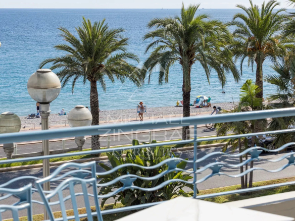 View of the Mediterranean Sea from a terrace with palm trees and a beach in Nice.