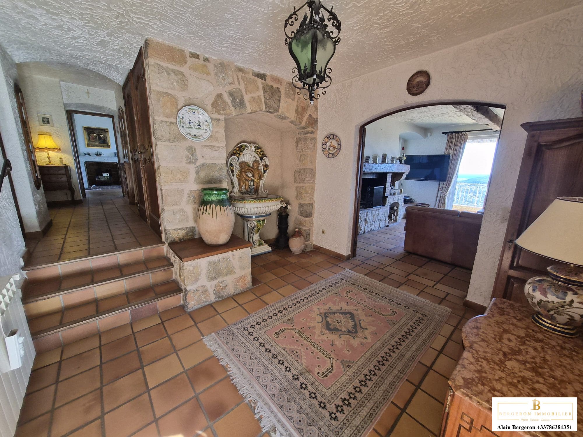 Intérieur d'une villa avec un hall d'entrée en pierre et un salon spacieux.