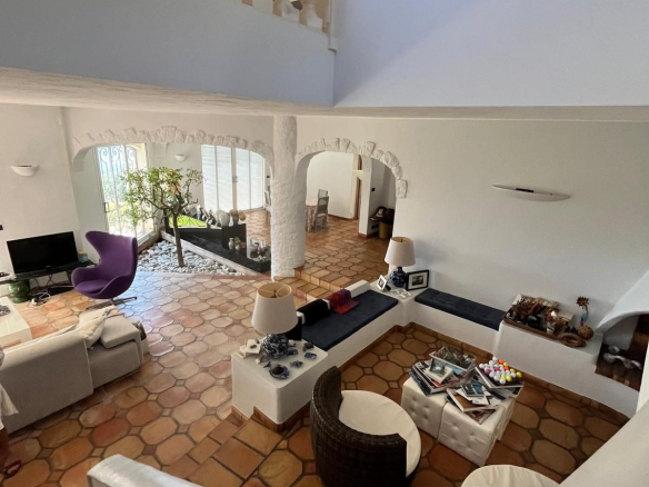 Interior of a modern villa with a large, bright living room and terracotta tile flooring.