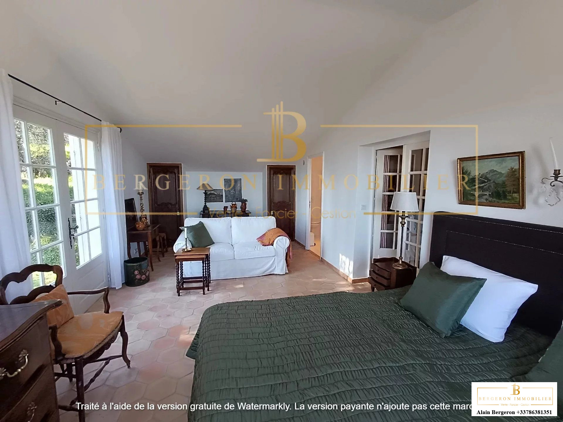 Chambre spacieuse d'une villa avec salon attenant, fenêtres offrant une vue panoramique.