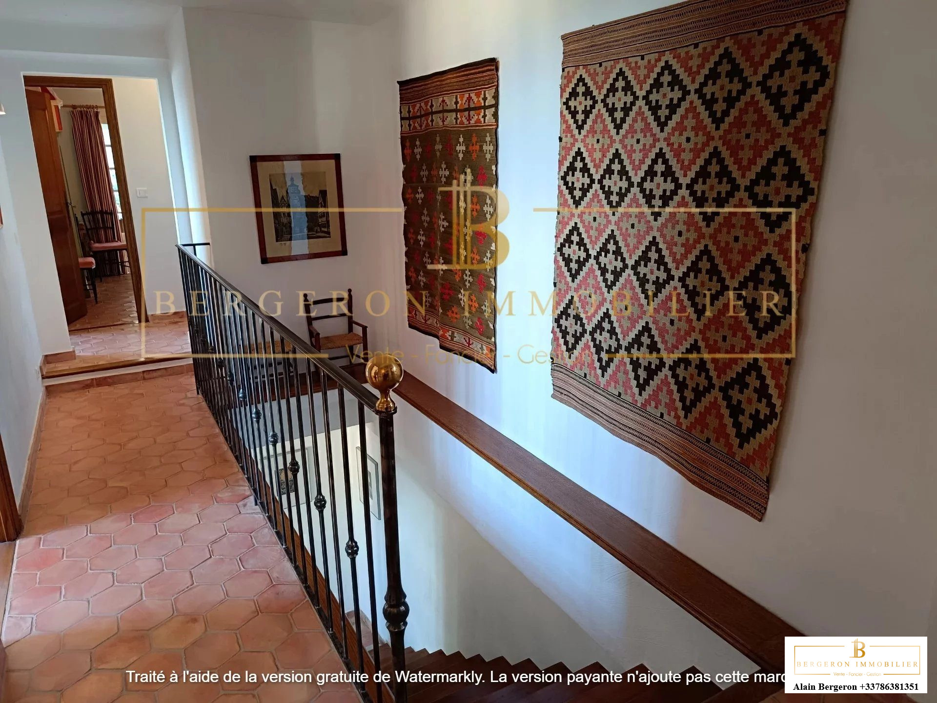 Intérieur d'une villa avec un couloir décoré de tapis et une balustrade en fer forgé.