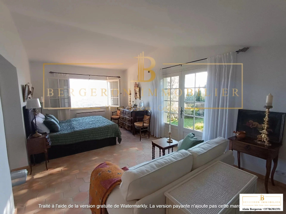 Intérieur d'une villa spacieuse avec lit, canapé et grandes fenêtres offrant une vue panoramique.