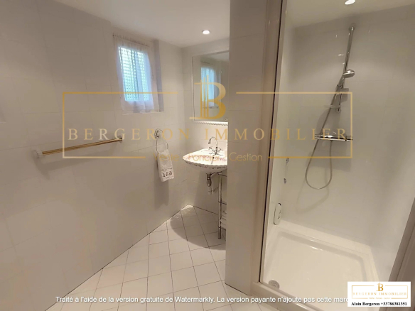 Salle de bain moderne avec douche et carrelage blanc dans une villa.