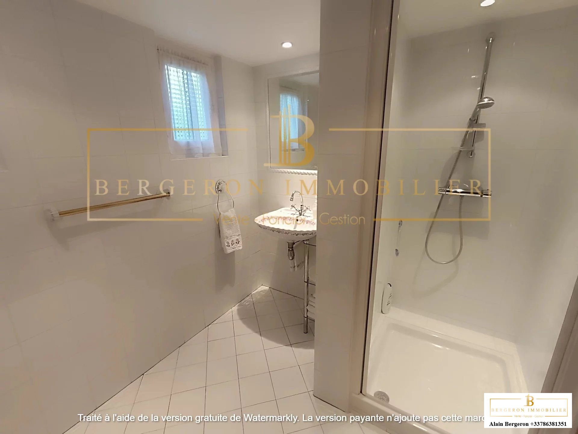 Salle de bain moderne avec douche et carrelage blanc dans une villa.