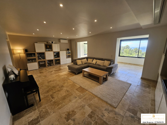 Intérieur d'une maison spacieuse à Cabris, salon lumineux avec canapé et vue sur la nature.
