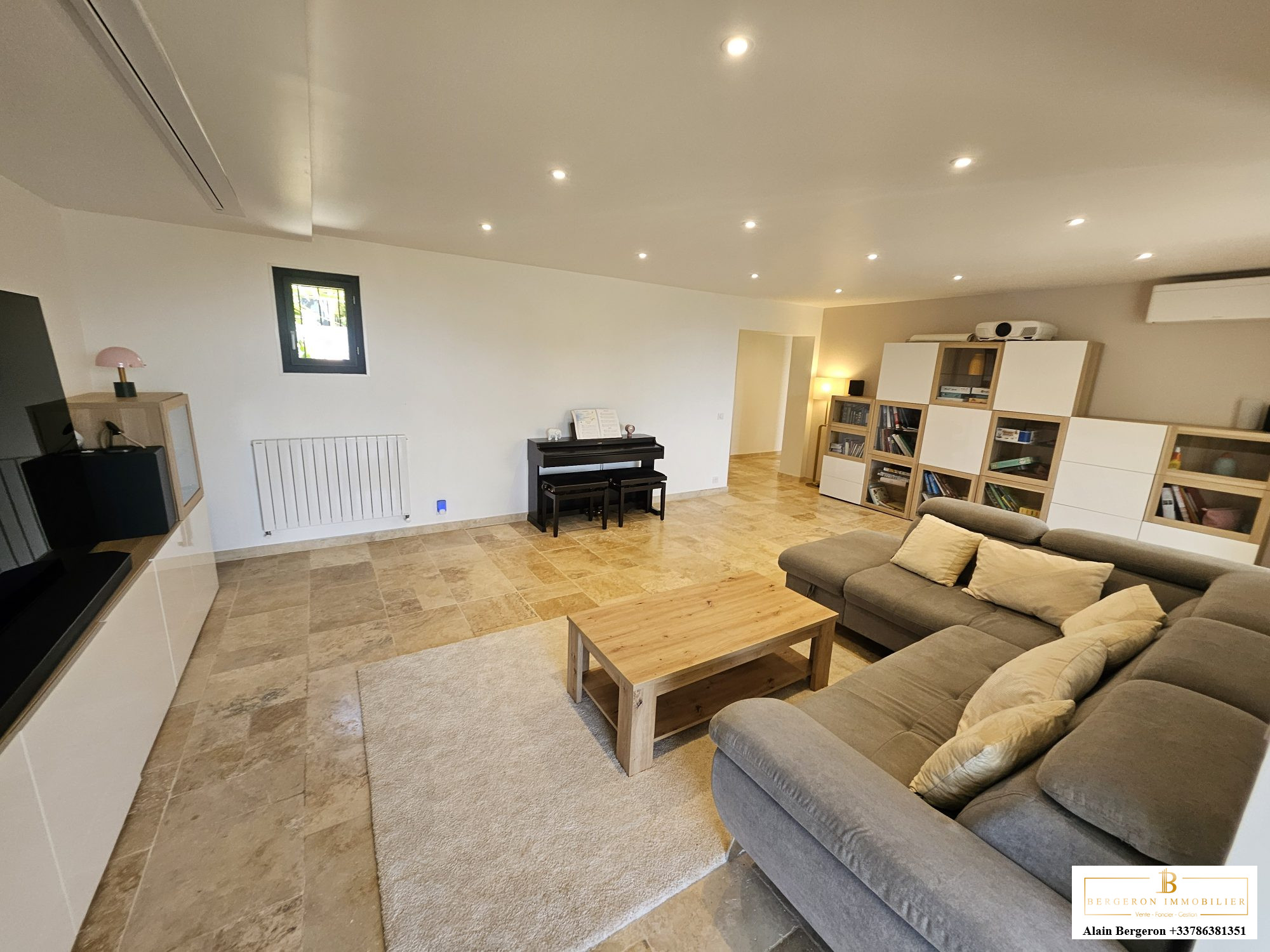 Intérieur d'une maison spacieuse avec salon lumineux, canapé et piano.