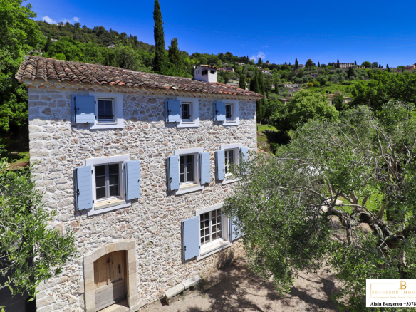 Bastide provençale en pierre avec volets bleus, entourée d'un jardin méditerranéen à Cabris.