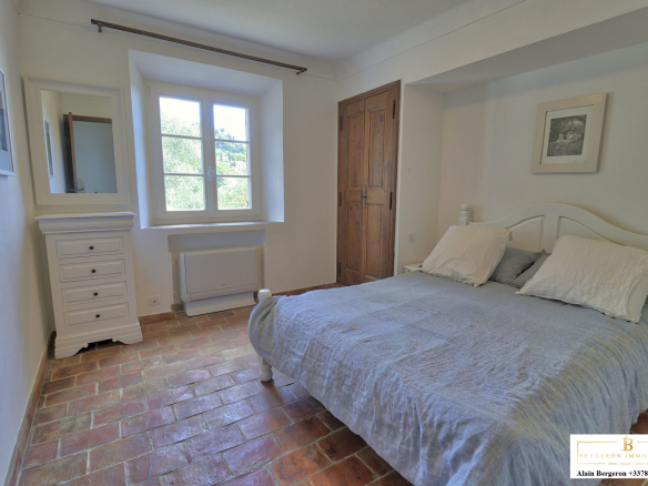 Chambre d'une bastide provençale avec lit double et fenêtre donnant sur le jardin.