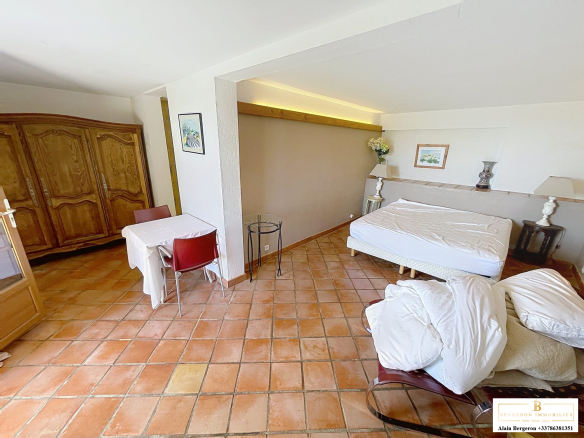 Interior of a bedroom in a house for sale in Spéracèdes, with a bed, a table and wooden furniture.