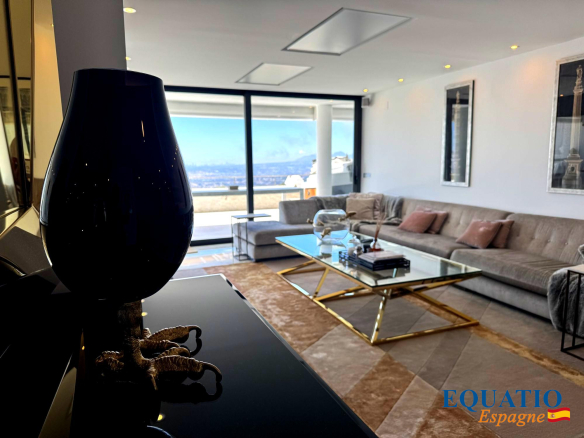 Luxurious living room with a beige sectional, glass coffee table, and a dark lamp in the foreground; large windows reveal a blue sky outside (logo 'EQUATIO Espagne' in corner).
