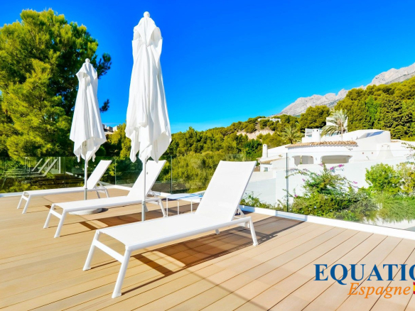 Terrasse ensoleillée avec chaises longues et parasols, vue sur la nature à Altea, Espagne.