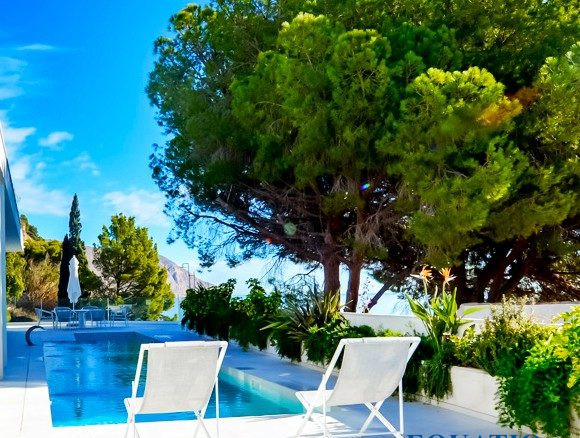 Villa contemporaine avec piscine et chaises longues, entourée de verdure à Altea, Espagne.