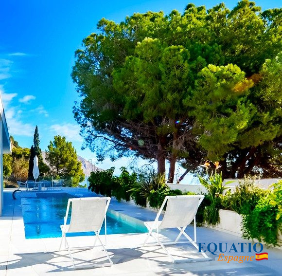 Villa contemporaine en bord de mer à Altea Villa contemporaine avec piscine et chaises longues, entourée de verdure à Altea, Espagne.