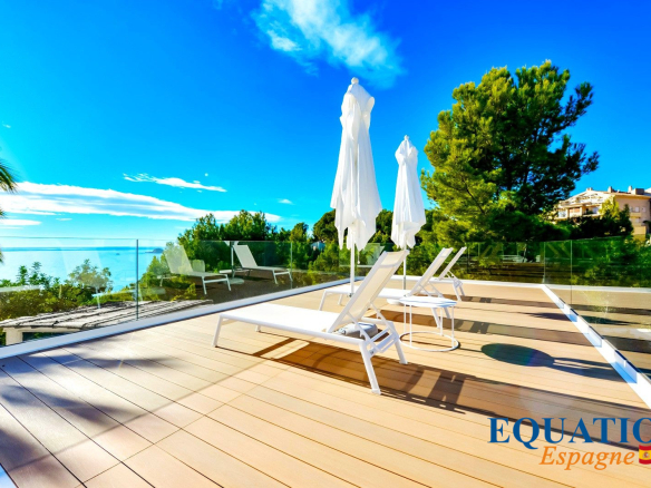 Terrasse ensoleillée avec chaises longues et parasols, vue sur la mer à Altea, Espagne.