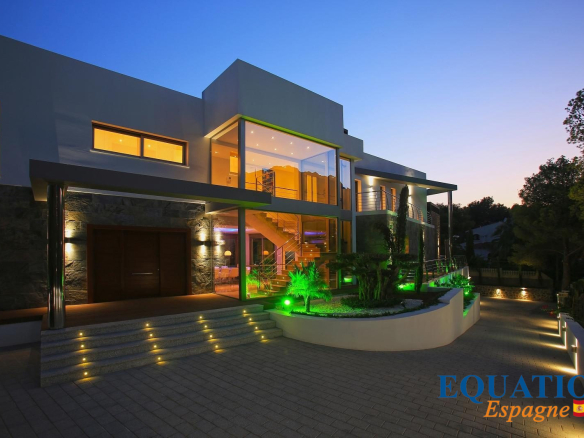 Villa moderne en première ligne de mer à Altea, Espagne, avec éclairage nocturne.