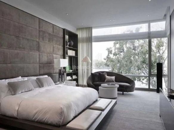 Master bedroom of a luxury apartment in Bangkok with a king-size bed and windows overlooking the outside.