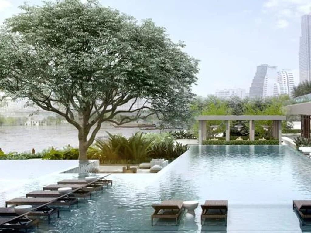 View of a luxury apartment with a swimming pool in Bangkok, Thailand, surrounded by greenery.