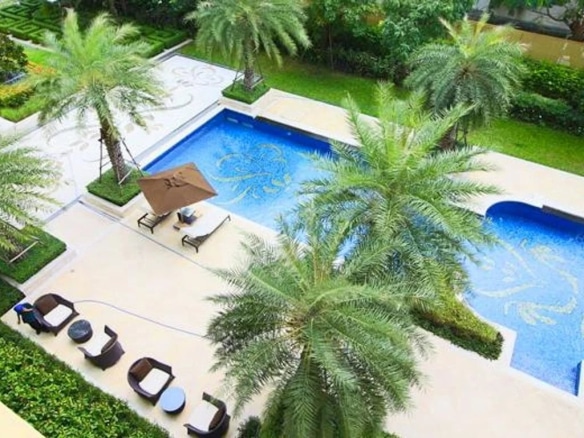 Vue d'une piscine entourée de palmiers dans un appartement de luxe à Bangkok.