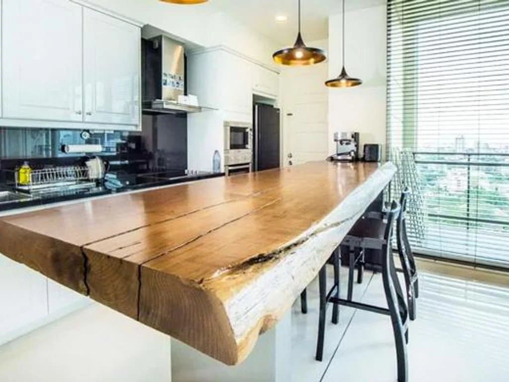 Cuisine moderne avec un grand plan de travail en bois dans un appartement de luxe à Bangkok.