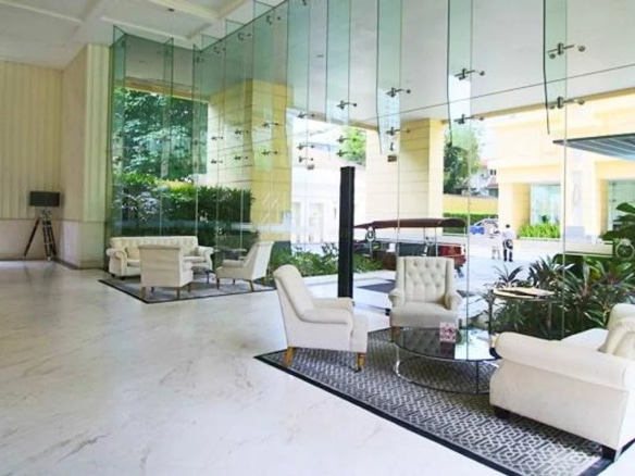 Intérieur d'un hall d'entrée d'appartement de luxe avec des fauteuils blancs et des murs en verre à Bangkok.