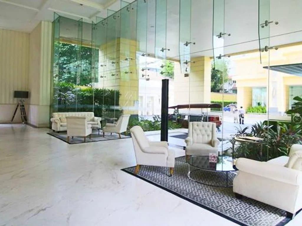 Intérieur d'un hall d'entrée d'appartement de luxe avec des fauteuils blancs et des murs en verre à Bangkok.