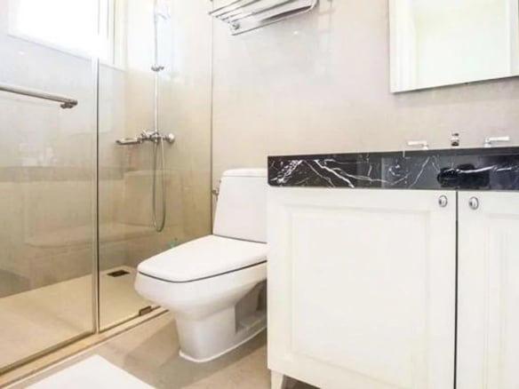 Salle de bain moderne avec douche, toilettes et meuble sous lavabo en marbre.