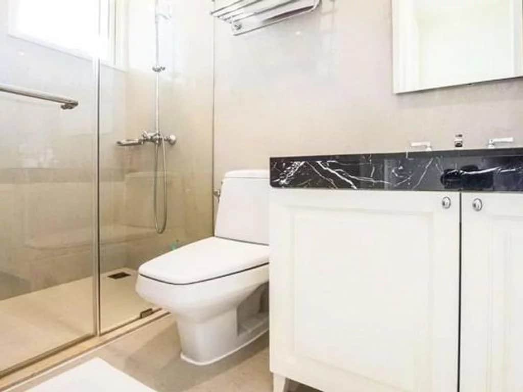 Salle de bain moderne avec douche, toilettes et meuble sous lavabo en marbre.