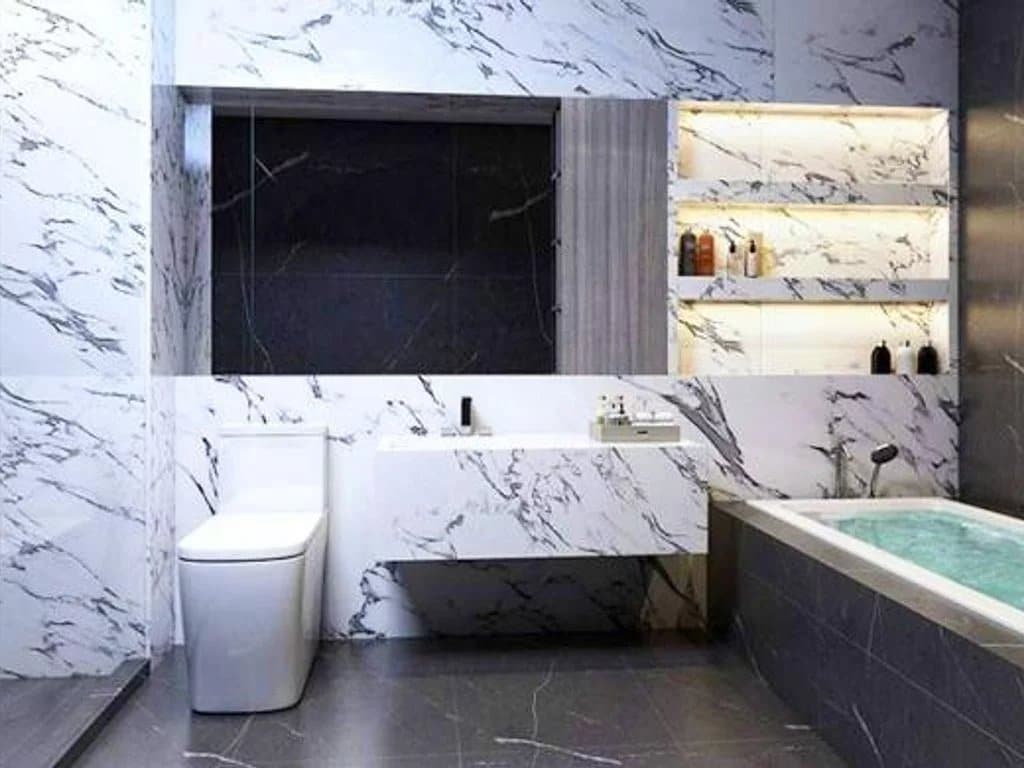 Modern bathroom with bathtub and toilet, decorated with marble.
