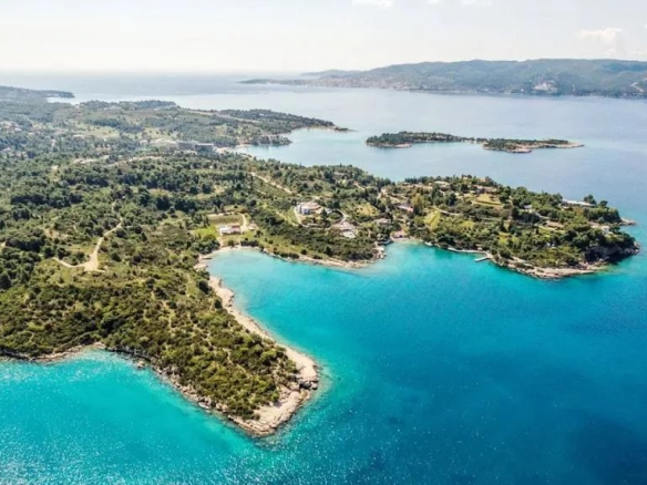 Vue aérienne d'un domaine en bord de mer à Porto Heli, avec des eaux turquoise et des îles environnantes.