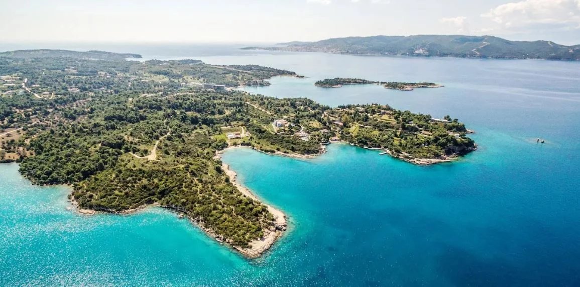 Domaine en bord de mer à Porto Heli Vue aérienne d'un domaine en bord de mer à Porto Heli, avec des eaux turquoise et des îles environnantes.