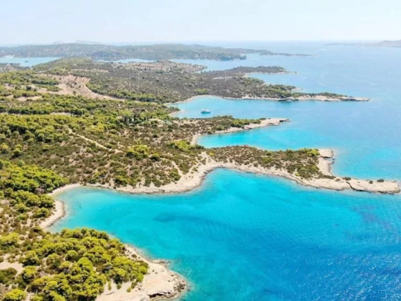 Vue aérienne d'un domaine en bord de mer à Porto Heli, avec des eaux turquoise et des côtes verdoyantes.