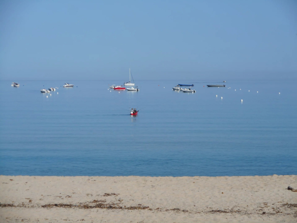 Vue de la plage de Calcatoggio avec des bateaux au large et une mer calme
