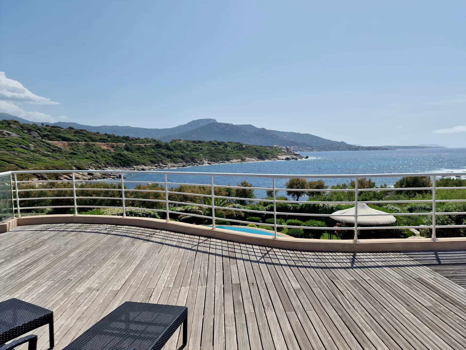 Vue sur la mer depuis la propriété Vue dégagée sur la mer depuis une terrasse en bois avec des chaises noires.