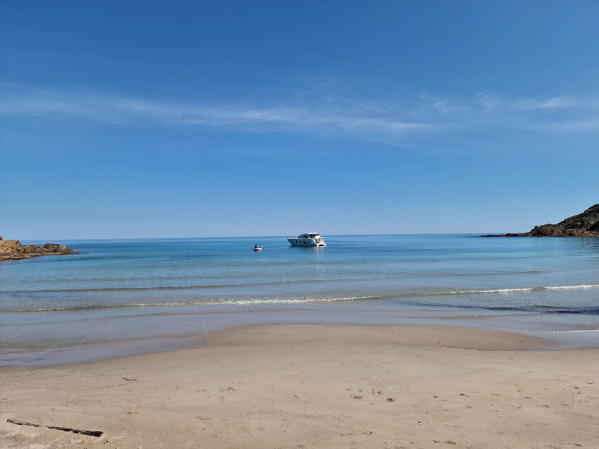 Plage de Conca, côte Fautea Plage calme avec un bateau au large et ciel dégagé à Conca, côte Fautea.
