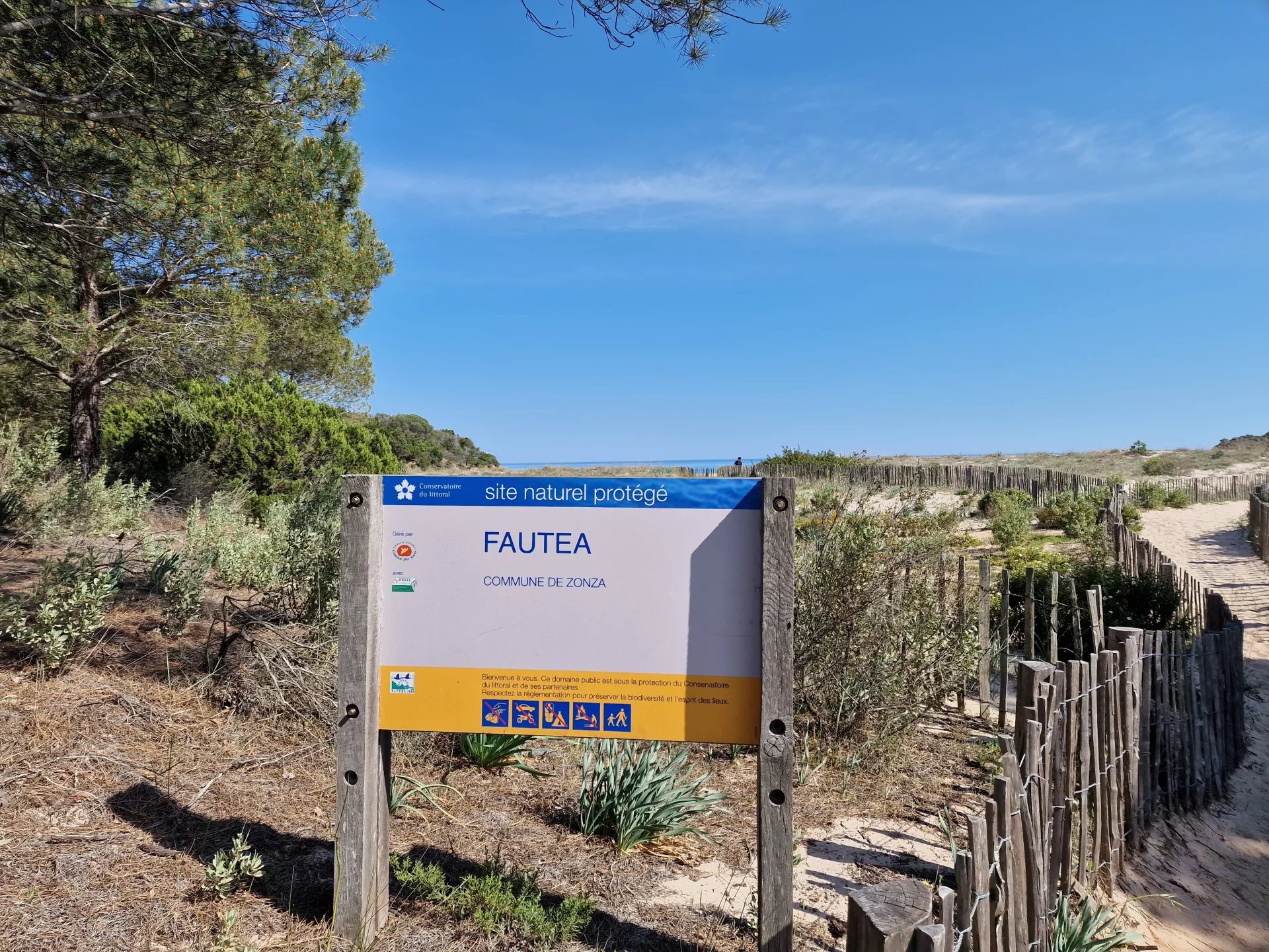 Site naturel protégé de Fautea Panneau d'entrée du site naturel protégé de Fautea avec des paysages côtiers en arrière-plan.