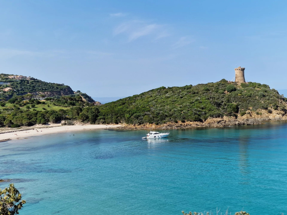 Vue de la mer turquoise avec un bateau et une tour sur la côte de Fautea, près de Conca.