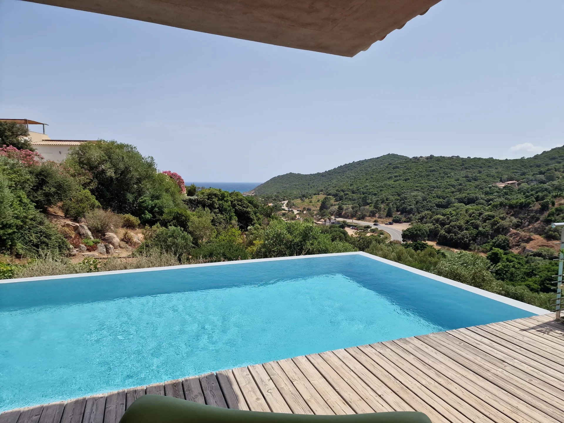 Villa d’architecte avec piscine Vue de la piscine d'une villa d'architecte avec paysage verdoyant et mer au loin.