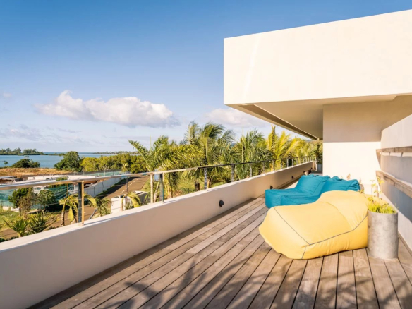 Terrasse moderne avec fauteuils confortables, vue sur le lagon et la végétation environnante.