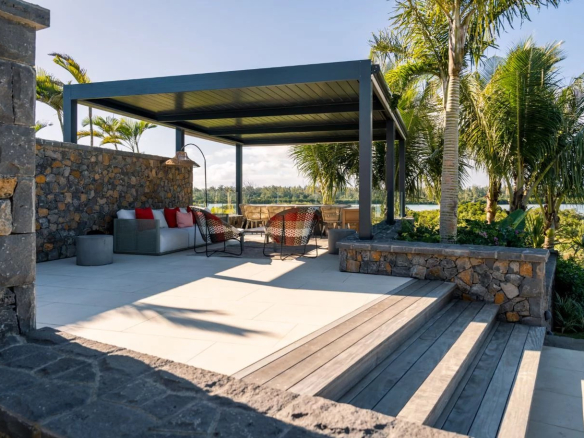 Terrasse moderne avec mobilier de jardin, vue sur le lagon et les palmiers.