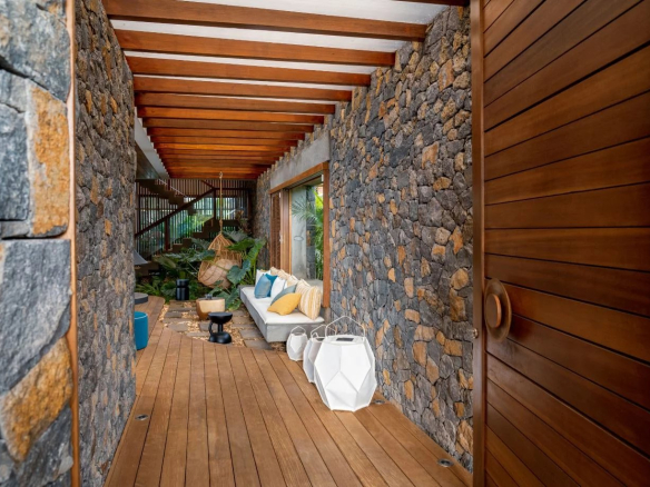 Intérieur d'une propriété moderne avec murs en pierre et un sol en bois, décor tropical.