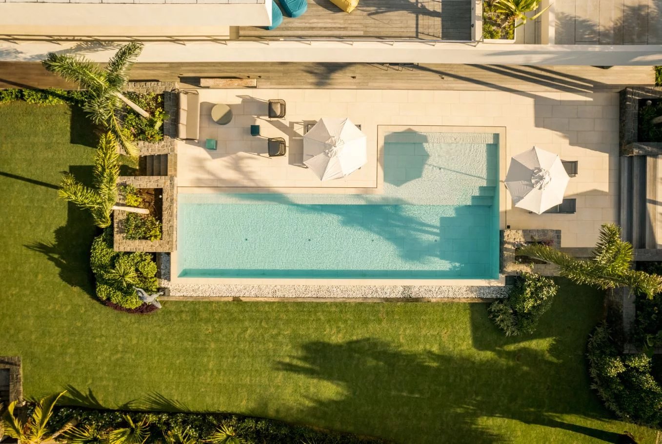 Piscine d’une somptueuse propriété Vue aérienne d'une piscine entourée de pelouse et de parasols dans une propriété de luxe.