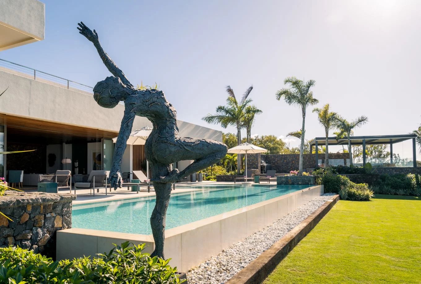 Propriété de luxe avec piscine et sculpture Propriété moderne avec piscine, sculpture et jardin, face à un lagon.