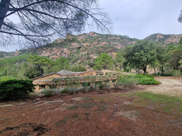 Bastide en pierre entourée de verdure et de montagnes, située dans un domaine privé.