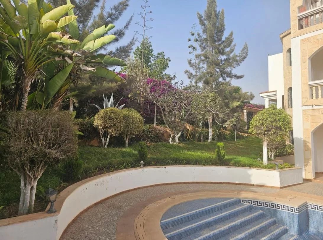 Jardin de la villa Prestige à Illigh Jardin d'une villa avec piscine, arbres et plantes à Agadir, vue sur la mer et les montagnes.