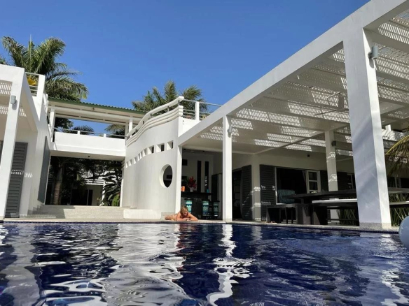 Vue de la piscine et de la propriété moderne avec un espace extérieur ensoleillé.