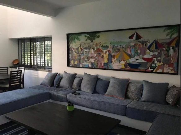 Intérieur d'une propriété avec un grand canapé et une œuvre d'art murale colorée.