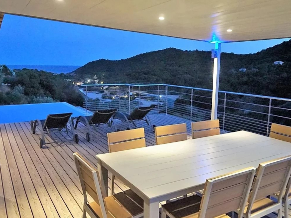 Terrasse en bois avec vue sur la mer et la montagne, équipée d'une table et de chaises, à Conca.