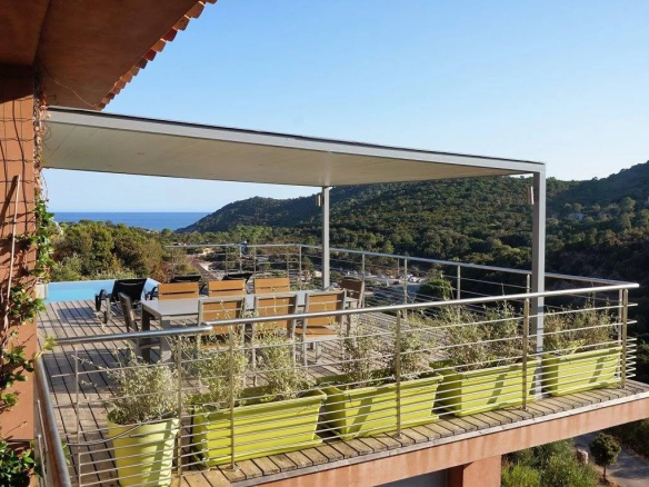 Vue d'une villa d'architecte avec terrasse et piscine surplombant la mer et la montagne à Conca.