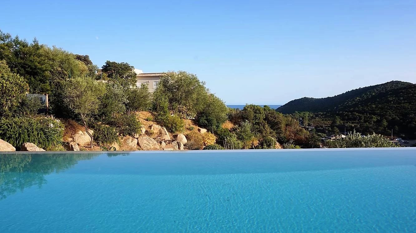 Villa d’architecte avec piscine à débordement Vue de la piscine à débordement d'une villa d'architecte avec paysage montagneux et vue sur la mer.