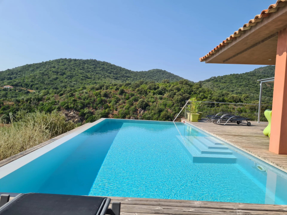 Vue de la piscine à débordement d'une villa d'architecte avec montagnes en arrière-plan à Conca.